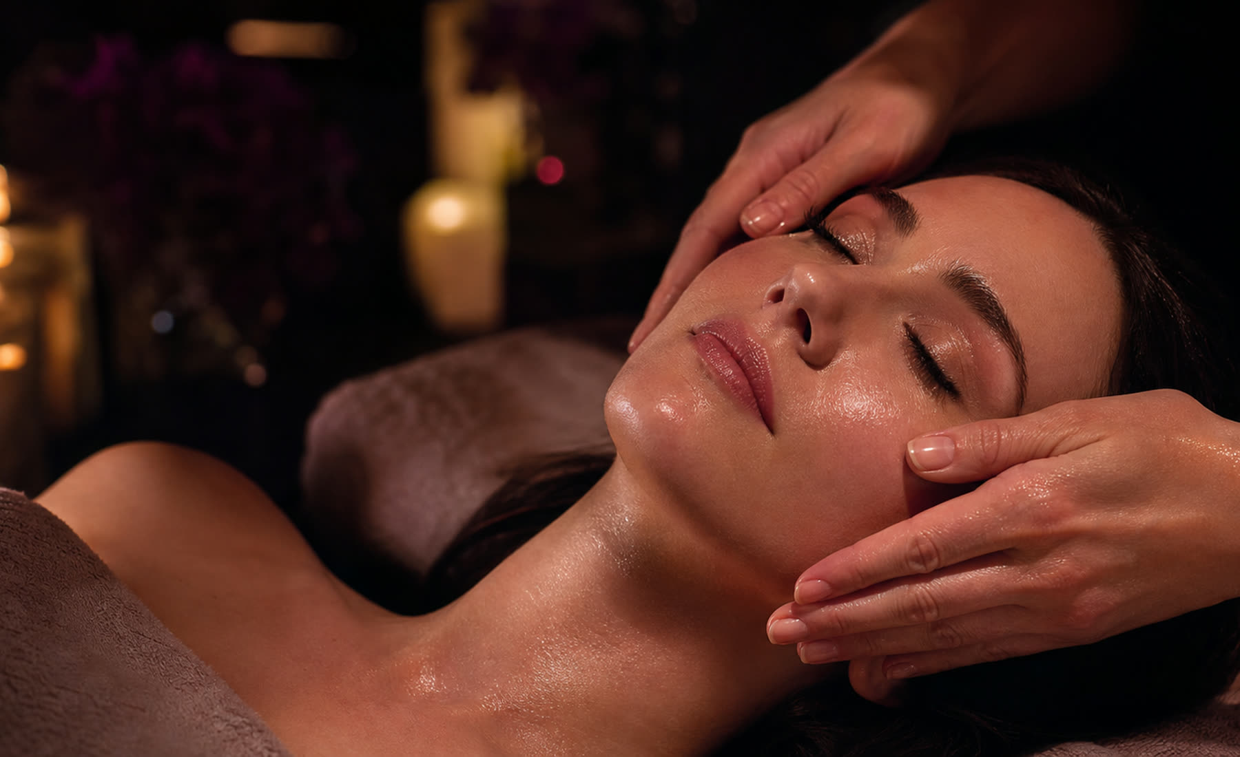 Manos de la esteticista durante un facial, a la luz de las velas